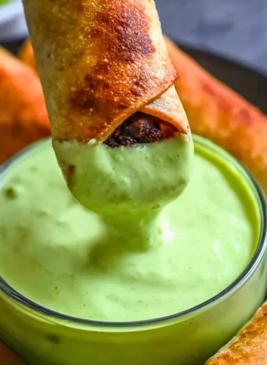 Baked black bean taquitos on a plate garnished with salsa and avocado
