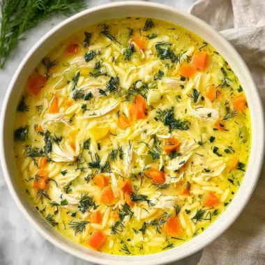 Bowl of delicious Greek Lemon Chicken Soup garnished with lemon and herbs.