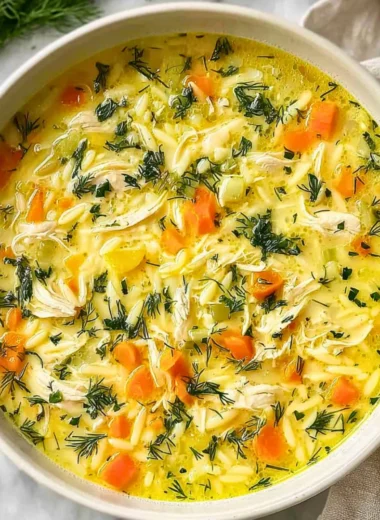 Bowl of delicious Greek Lemon Chicken Soup garnished with lemon and herbs.