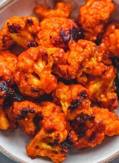 Bowl of easy buffalo cauliflower bites garnished with fresh herbs