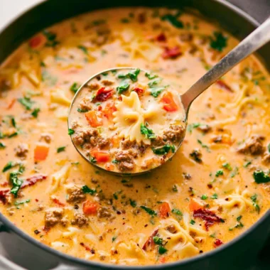 Bowl of Italian Sausage Pasta Soup with vegetables and herbs