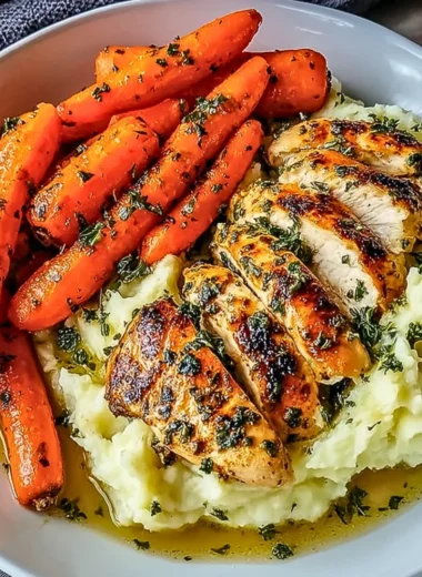 Delicious garlic herb chicken with mashed potatoes and glazed carrots on a plate.