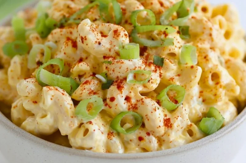 Delicious deviled egg pasta salad in a bowl, garnished with herbs.