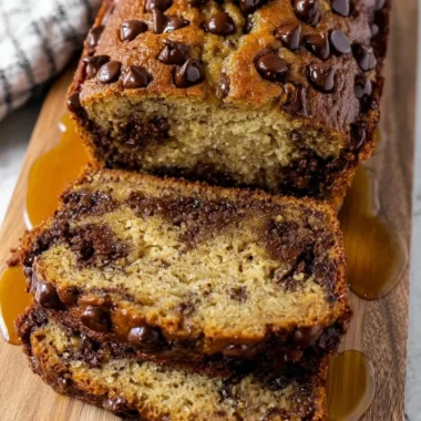 Slice of easy chocolate chip banana bread on a wooden cutting board