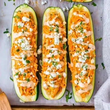 Buffalo chicken stuffed zucchini boats on a platter with toppings