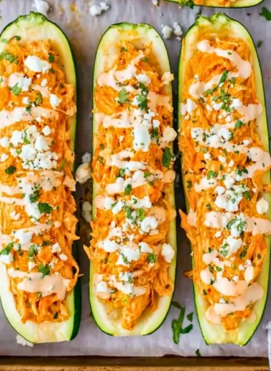 Buffalo chicken stuffed zucchini boats on a platter with toppings