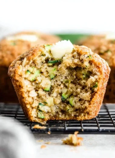 Gluten free zucchini muffins on a wooden table with fresh zucchini slices.