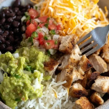Grilled chicken burrito bowl featuring rice, beans, and fresh toppings.
