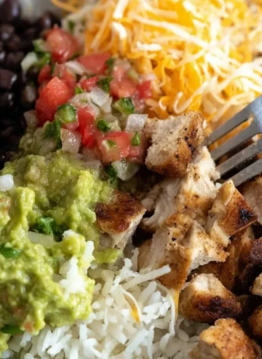 Grilled chicken burrito bowl featuring rice, beans, and fresh toppings.