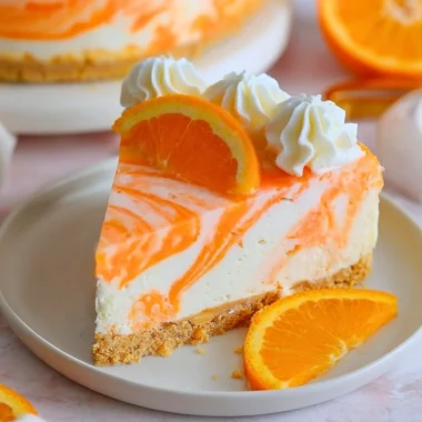 No-bake orange creamsicle cheesecake topped with orange slices and cream.