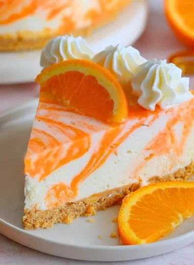 No-bake orange creamsicle cheesecake topped with orange slices and cream.