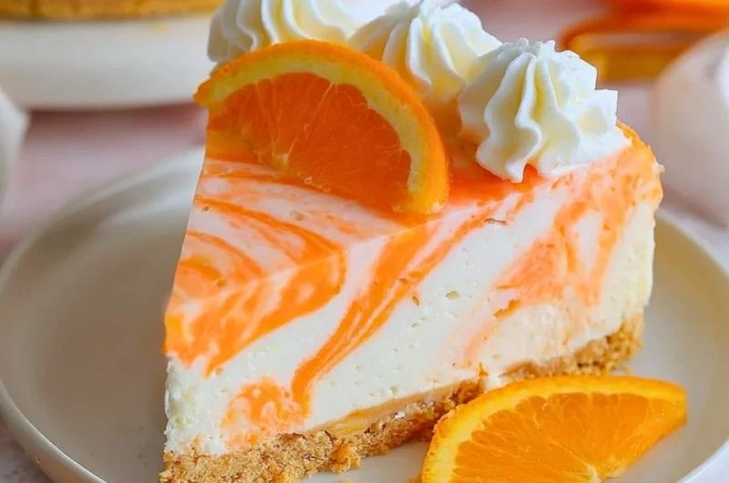 No-bake orange creamsicle cheesecake topped with orange slices and cream.
