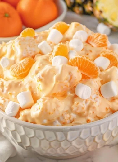 Bowl of refreshing Orange Fluff Salad with whipped cream and orange slices