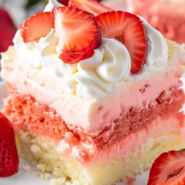 Close-up of a slice of strawberry cheesecake poke cake on a plate