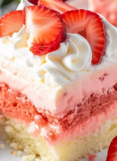 Close-up of a slice of strawberry cheesecake poke cake on a plate