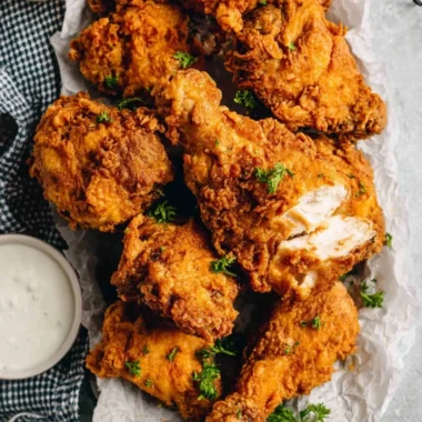 Delicious buttermilk fried chicken plated with a side of dipping sauce.