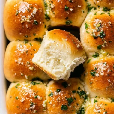 Freshly baked garlic bread rolls with a golden crust and garnished herbs