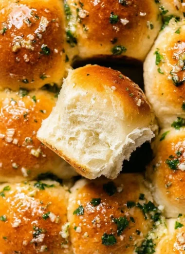 Freshly baked garlic bread rolls with a golden crust and garnished herbs