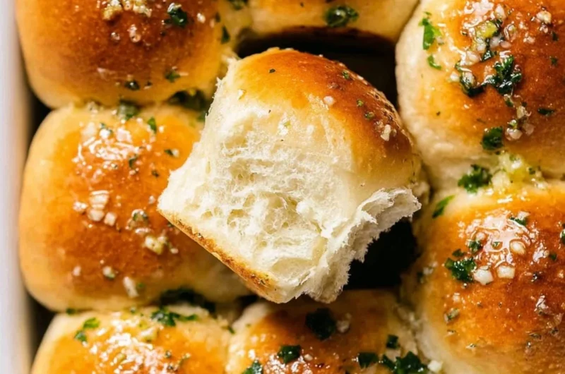 Freshly baked garlic bread rolls with a golden crust and garnished herbs