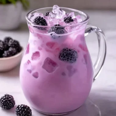 Homemade blackberry coconut drink in a glass with fresh berries and coconut.