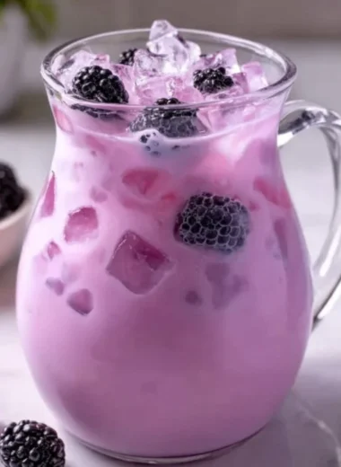 Homemade blackberry coconut drink in a glass with fresh berries and coconut.