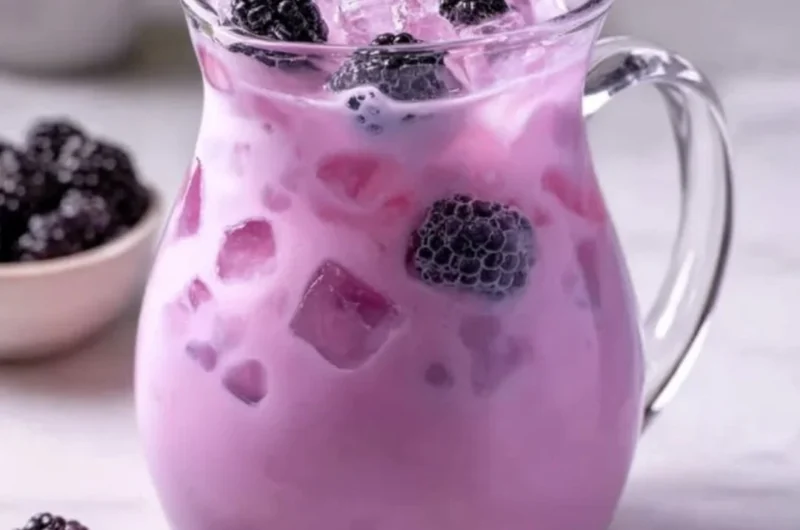 Homemade blackberry coconut drink in a glass with fresh berries and coconut.