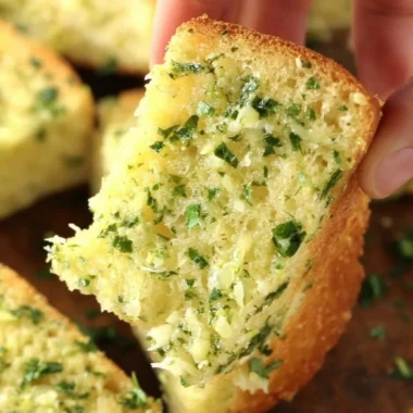 Homemade garlic bread with butter and herbs on a wooden table