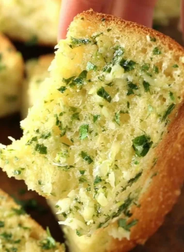 Homemade garlic bread with butter and herbs on a wooden table