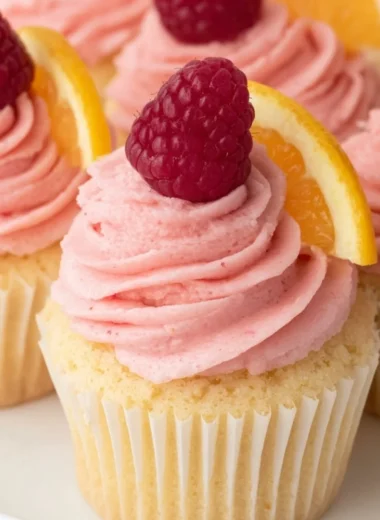 Lemon cupcakes topped with raspberry buttercream frosting served on a plate