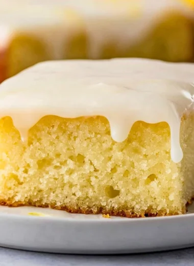 Delicious lemonade poke cake topped with lemon frosting and fresh lemons.