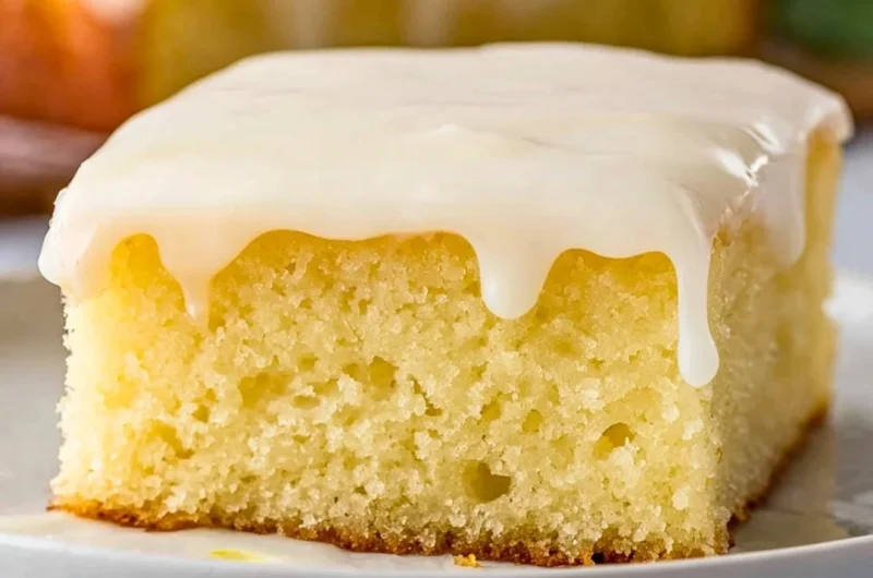 Delicious lemonade poke cake topped with lemon frosting and fresh lemons.