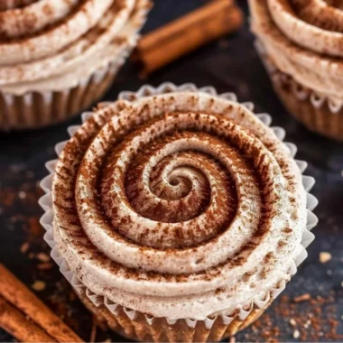 Mini no bake cinnamon roll cheesecakes topped with cinnamon swirl.