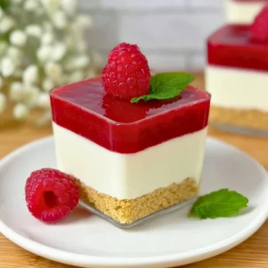Delicious raspberry cheesecake in a glass with layers of cream and fruit.