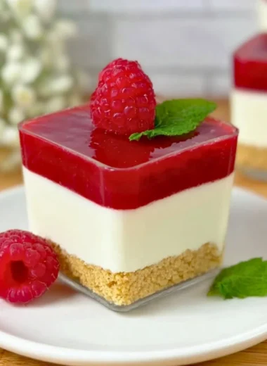 Delicious raspberry cheesecake in a glass with layers of cream and fruit.