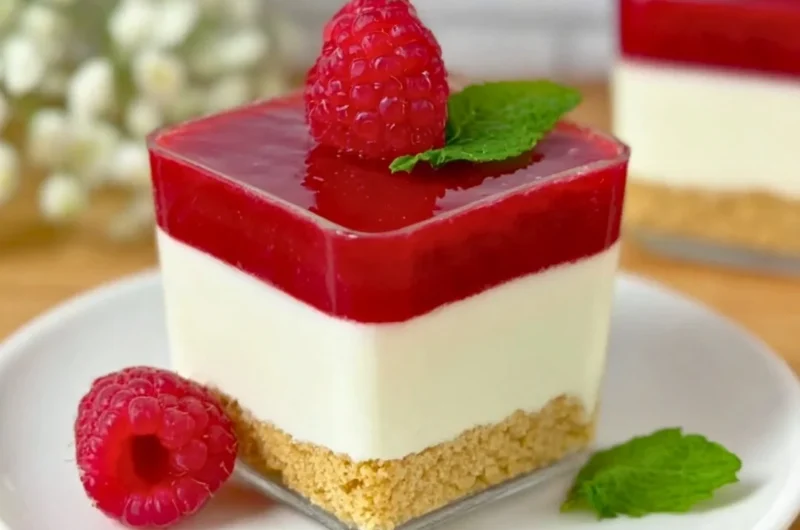 Delicious raspberry cheesecake in a glass with layers of cream and fruit.