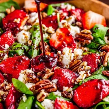 Fresh Spinach Strawberry Salad with Pecans garnished with dressing.