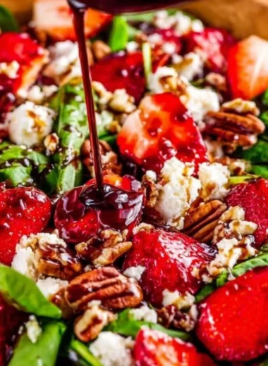 Fresh Spinach Strawberry Salad with Pecans garnished with dressing.