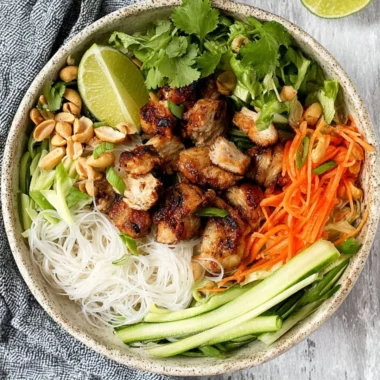Vietnamese noodle bowl with lemongrass chicken garnished with fresh herbs